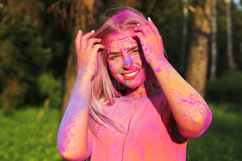 Adorable blonde model posing covered with a colorful dry paint a. Adorable blonde woman posing covered with a colorful dry paint at the park royalty free stock image
